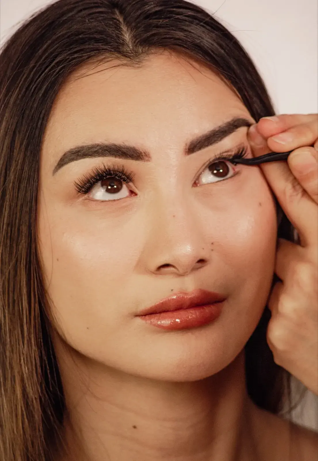 Pose de faux-cils en backstage, regard levé, précision du geste