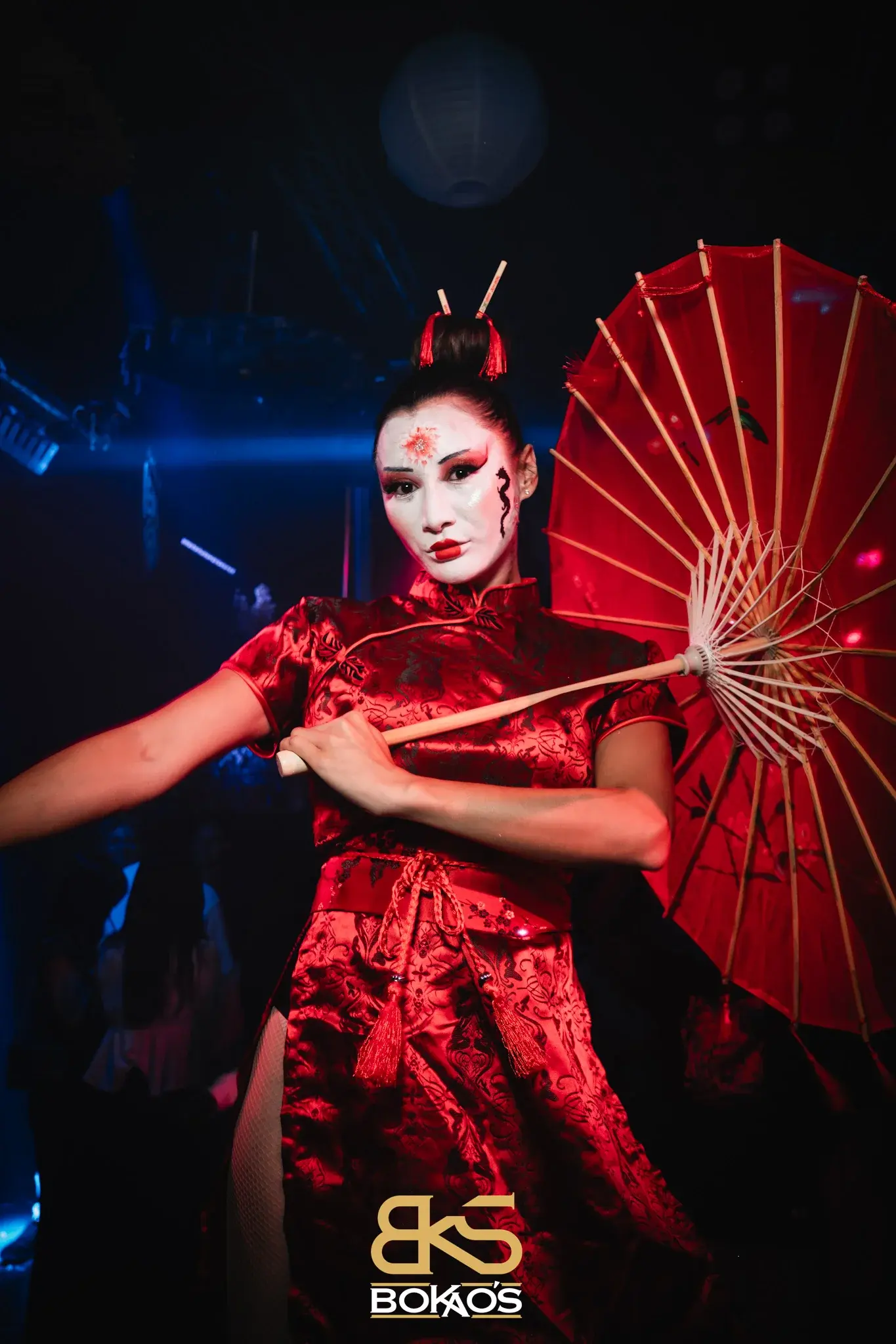 Plan américain avec ombrelle rouge traditionnelle, robe satinée fendue