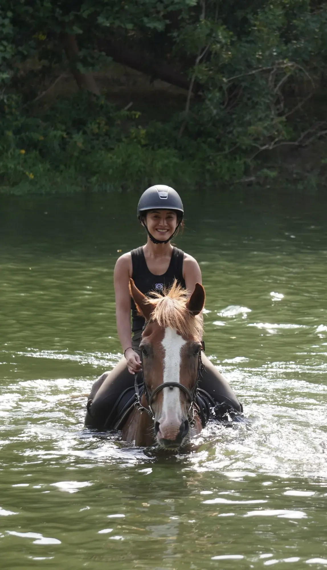 À cheval traversant une rivière, grand sourire face caméra
