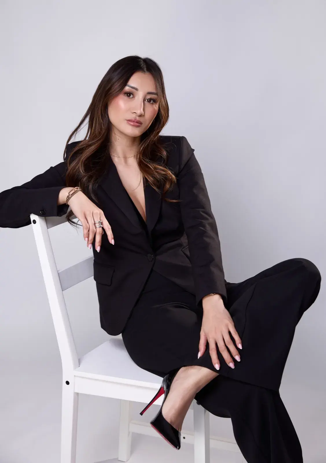 Assise en tailleur noir, jambe croisée, escarpins à semelle rouge