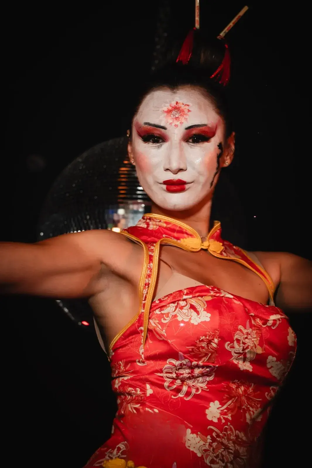 Portrait serré devant la boule à facettes, bras écartés en pose de danse