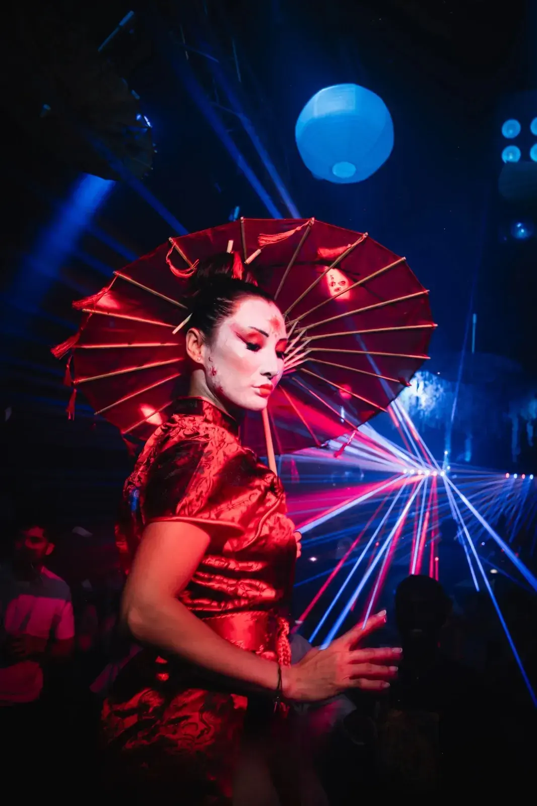 Profil en robe rouge satinée avec ombrelle, lasers de discothèque