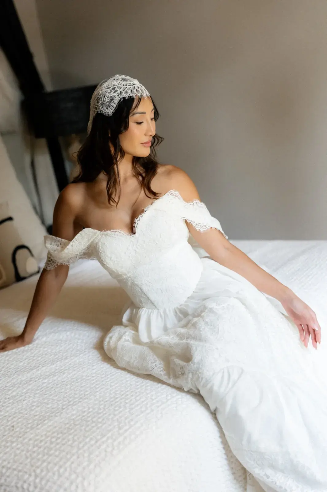 Allongée sur le lit en robe à épaules dénudées, regard au loin