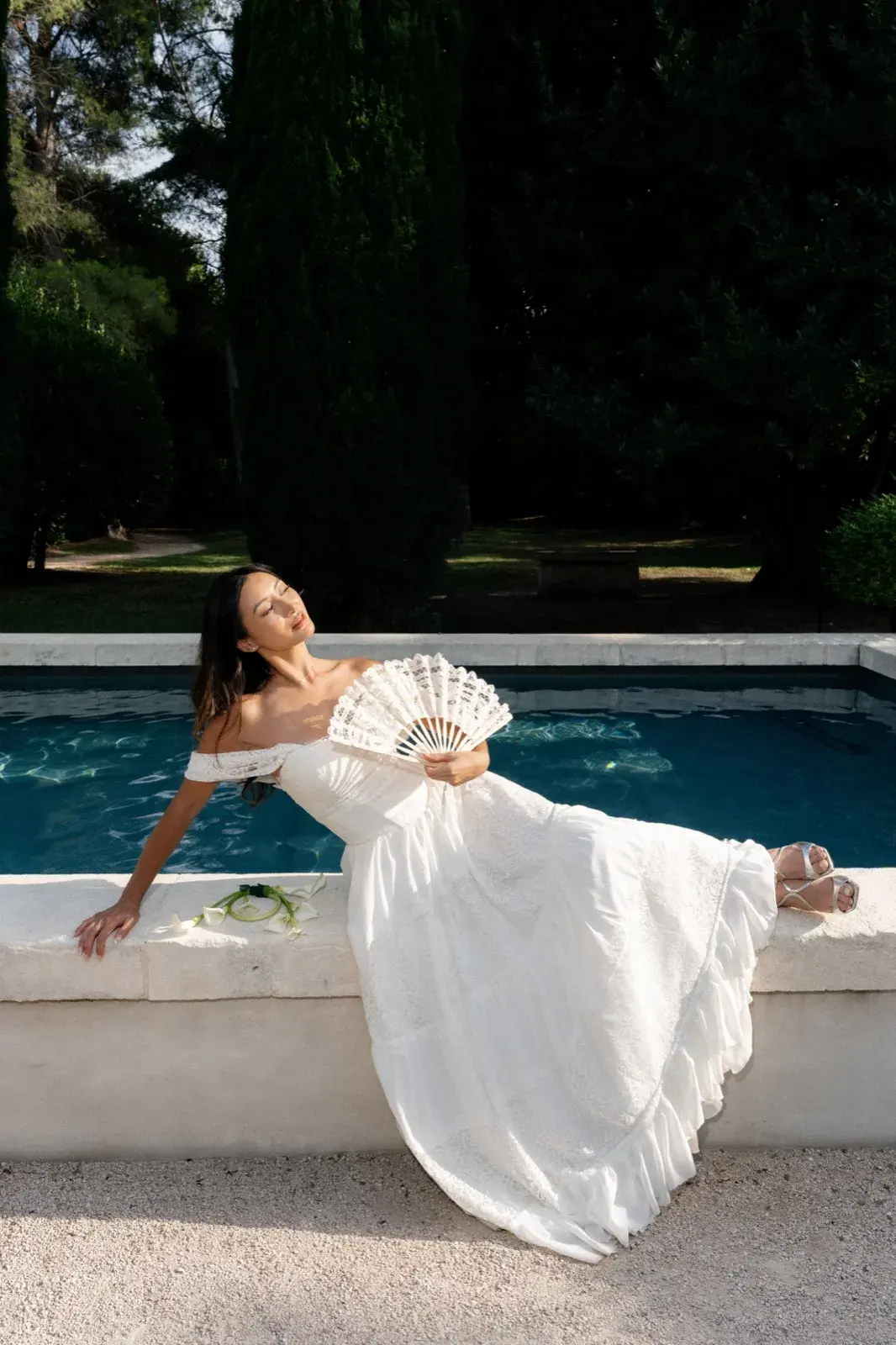 Allongée au bord de la piscine, éventail en dentelle à la main