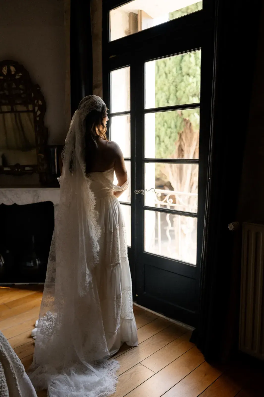 En contre-jour à la porte-fenêtre, voile de dentelle