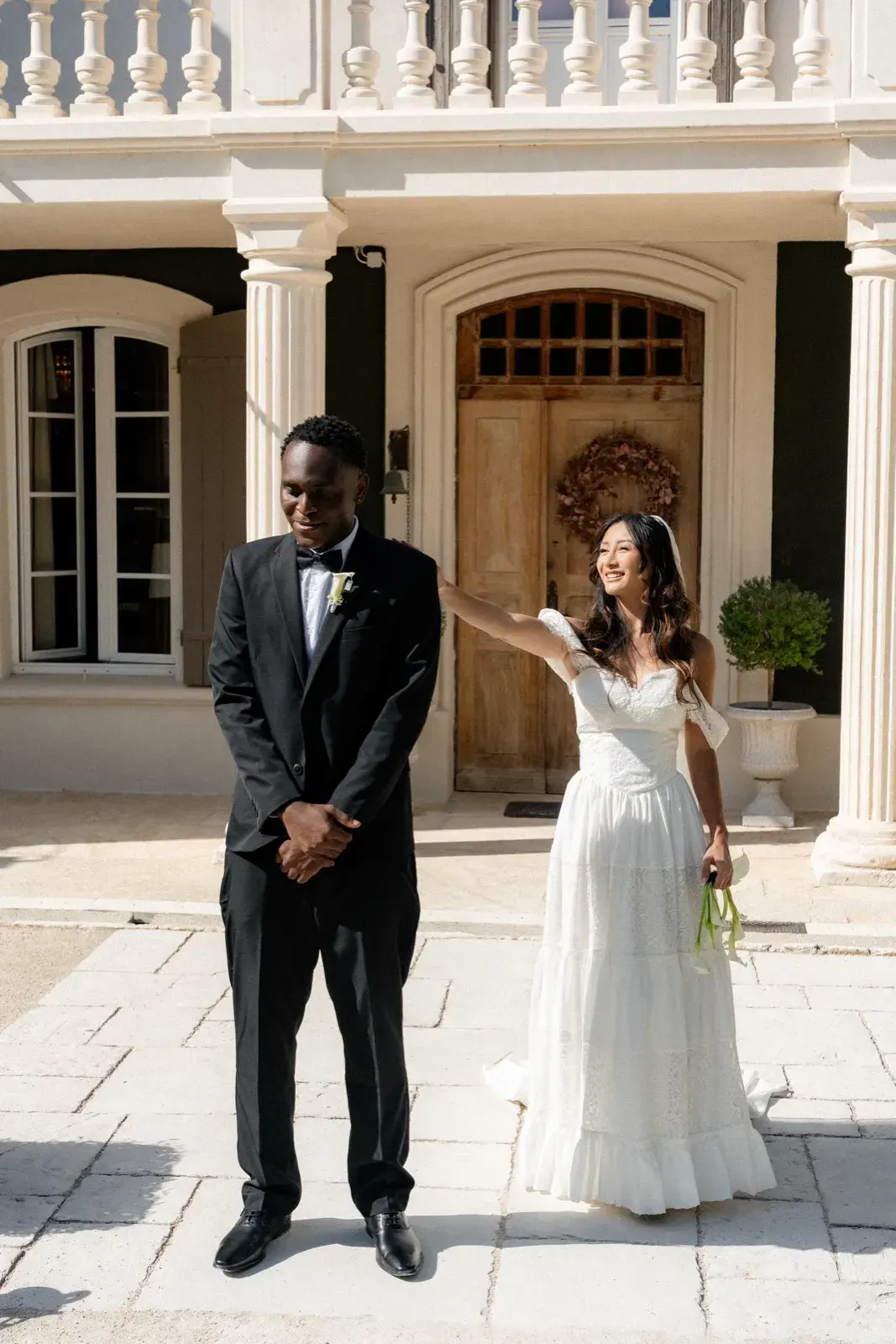 La mariée saluant, main sur l’épaule du marié