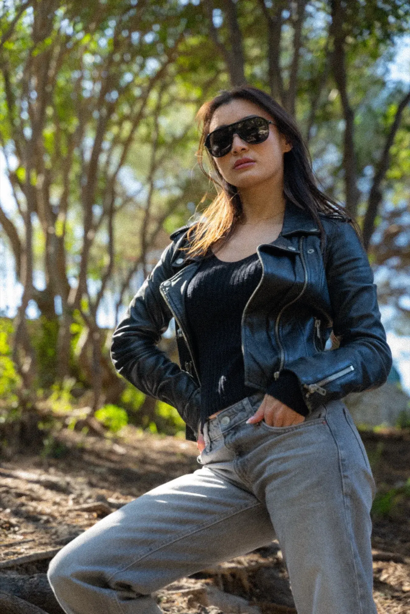 Sous-bois ensoleillé, perfecto noir, main dans la poche, jambe avancée