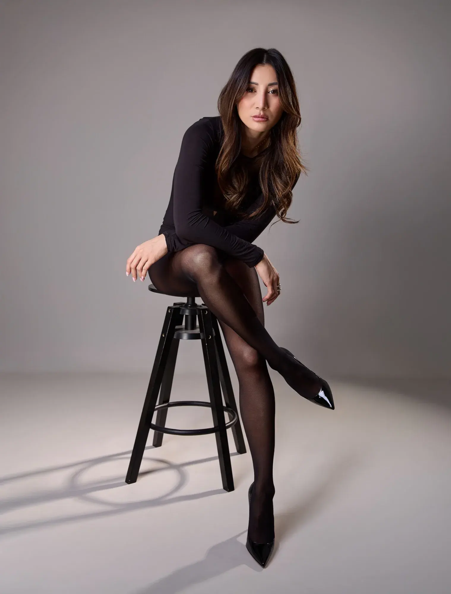 Assise sur un tabouret, penchée en avant, jambes croisées, regard intense
