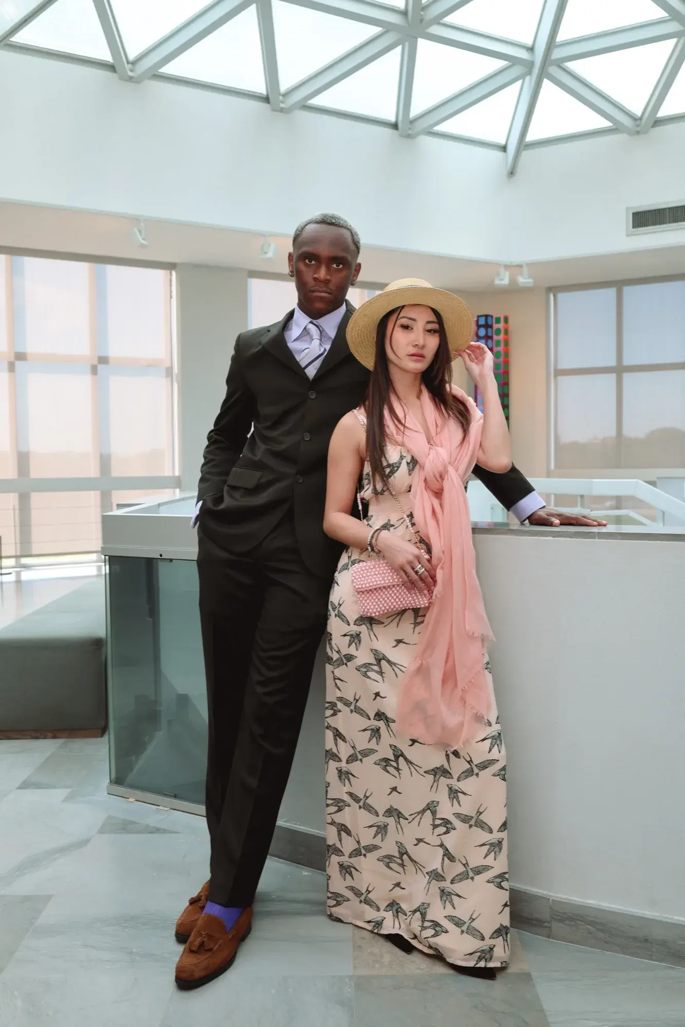 Duo en pied dans le showroom, main au canotier, robe longue imprimée